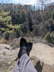 Creepers Merino wool toe socks with feet propped on a rock at a scenic overlook
