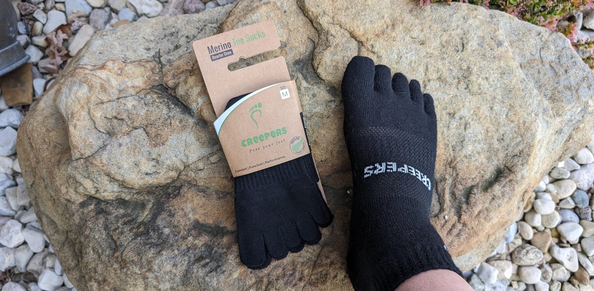 Creepers Merino toe socks in package and one being modeled on a foot.