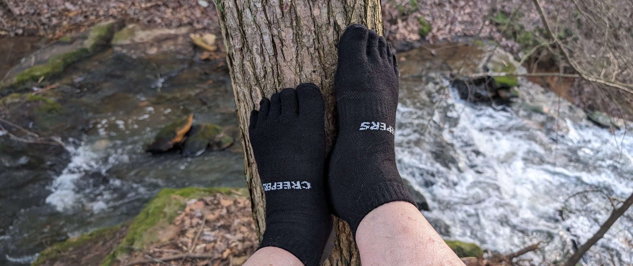Creepers Merino wool toe socks on a person with feet propped against a tree.