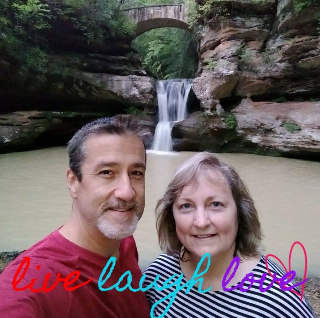 Dave & Michele of DiscoveringHockingHills.com standing in front of the Upper Falls at Old Man's Cave