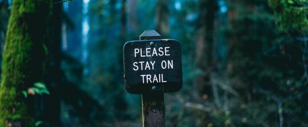 Wooden sign that says Please Stay on Trail